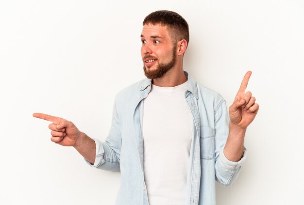 Junger kaukasischer Mann mit Diastema isoliert auf weißem Hintergrund, der auf verschiedene Kopienräume zeigt, einen von ihnen auswählt und mit dem Finger zeigt.