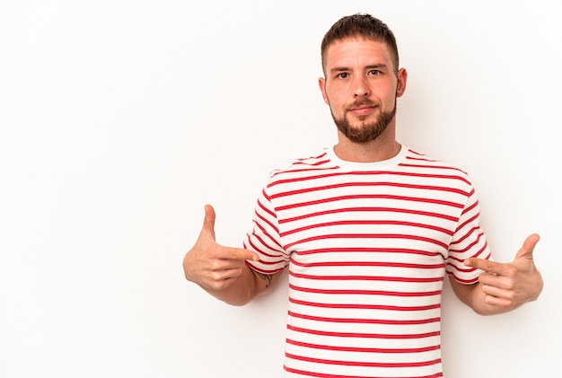 Junger kaukasischer Mann mit Diastema isoliert auf weißem Hintergrund, der mit der Hand auf einen Hemdkopierraum zeigt, stolz und selbstbewusst
