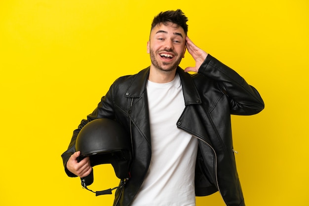 Junger kaukasischer Mann mit einem Motorradhelm auf gelbem Hintergrund mit Überraschungsausdruck isoliert