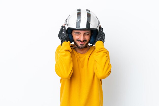 Junger kaukasischer Mann mit einem Motorradhelm, der auf weißem Hintergrund frustriert ist und die Ohren bedeckt