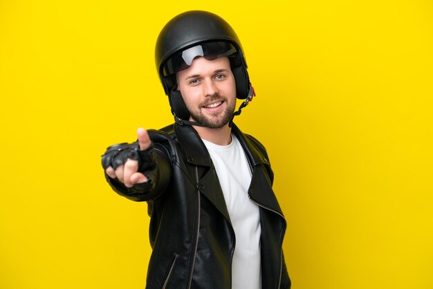 Junger kaukasischer Mann mit einem Motorradhelm isoliert auf gelbem Hintergrund, der einen Finger zeigt und hebt