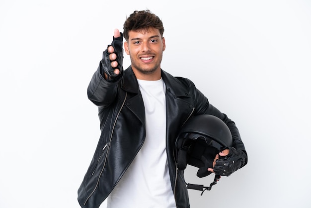 Junger kaukasischer Mann mit einem Motorradhelm isoliert auf weißem Hintergrund, der sich die Hände schüttelt, um ein gutes Geschäft abzuschließen
