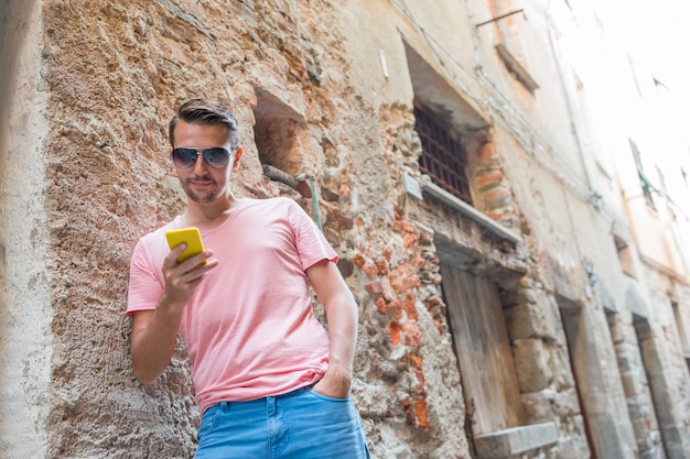 Junger kaukasischer Mann mit Handy in der europäischen Stadt