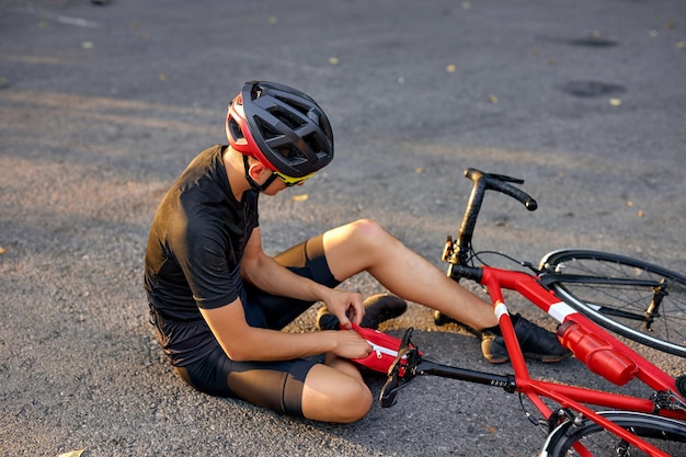 Junger kaukasischer mann mit knieverletzung beim radfahren auf der forststraße im sommer gesundheitsversorgung...