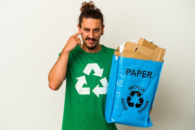 Junger kaukasischer Mann mit langen Haaren, die Karton auf weißem Hintergrund recyceln, der eine Enttäuschungsgeste mit dem Zeigefinger zeigt.