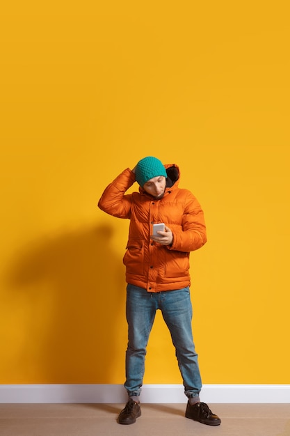 Junger kaukasischer Mann mit Smartphone Ganzkörper-Längenporträt über Gelb