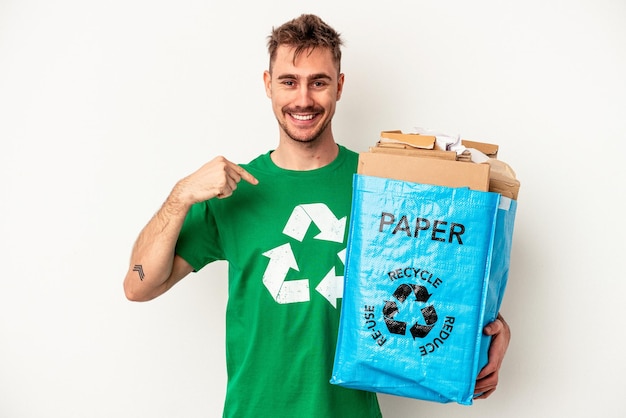 Junger kaukasischer Mann recyceltes Papier isoliert auf weißem Hintergrund Person, die mit der Hand auf einen Hemdkopierraum zeigt, stolz und selbstbewusst