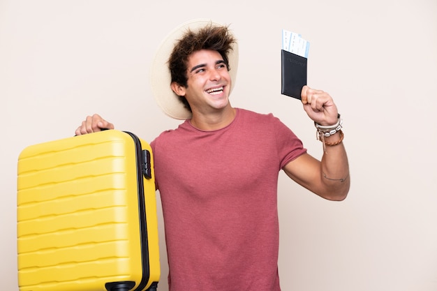 Junger kaukasischer mann über lokalisierter wand in den ferien mit koffer und pass