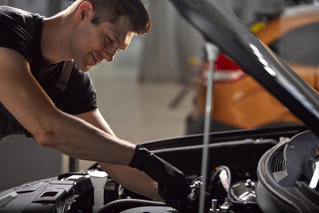 Foto junger kaukasischer professioneller automechaniker in einem autoservice