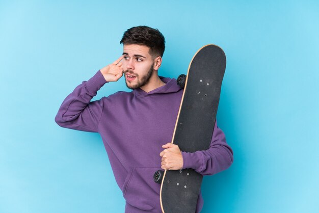 Junger kaukasischer Skatermann isoliert, der versucht, einen Klatsch zu hören.