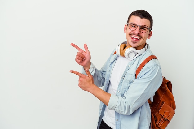 Junger kaukasischer Studentenmann, der Musik auf Weiß hört, das mit Zeigefingern auf einen Kopierraum zeigt und Aufregung und Verlangen ausdrückt.