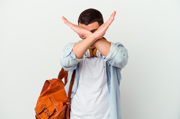 Junger kaukasischer Studentenmann, der Musik auf Weiß hört, der zwei Arme verschränkt hält, Verweigerungskonzept.