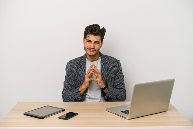 Junger kaukasischer Unternehmer, der mit Laptop, Handy und Tablet arbeitet