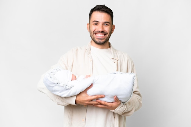 Junger kaukasischer Vater mit ihrem neugeborenen Baby vor isoliertem Hintergrund lächelt viel