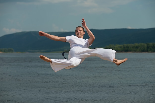 Junger Kerl bildet capoeira im Himmel aus