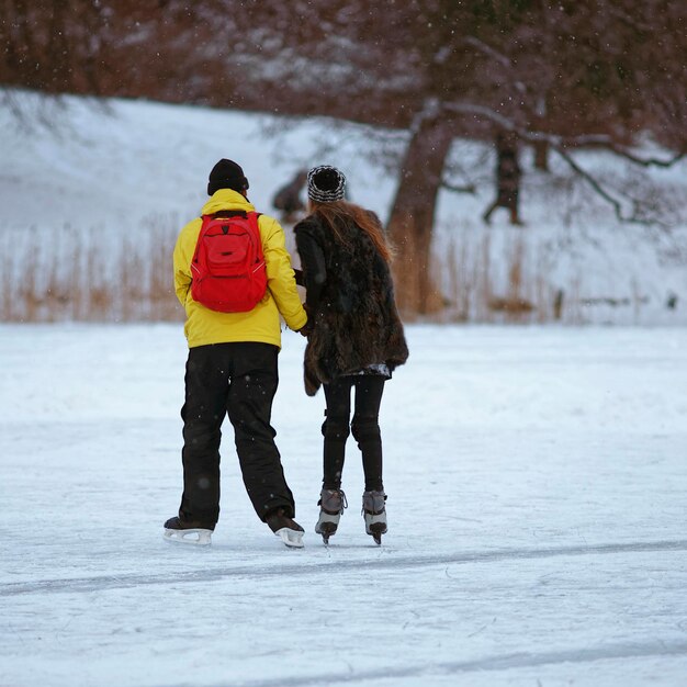 Junger Kerl lernt Mädchen Eislaufen auf dem zugefrorenen See im Winter Trakai. Schlittschuhlaufen umfasst jede Aktivität, die darin besteht, mit Schlittschuhen auf Eis zu fahren