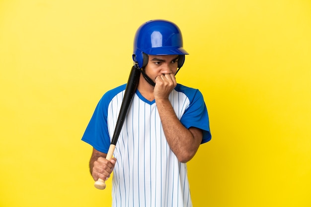 Junger kolumbianischer lateinischer Mann, der Baseball spielt, isoliert auf gelbem Hintergrund, der Zweifel hat