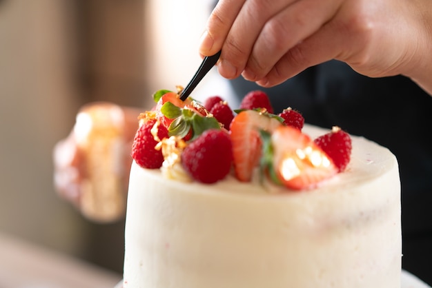 Junger konditor, der einen traditionellen roten samtkuchen in der küche kocht