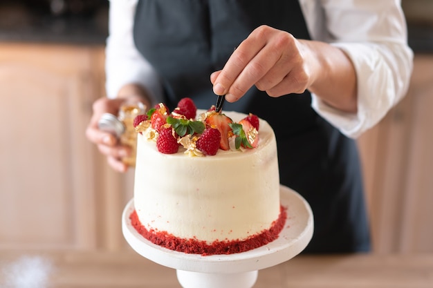 Junger Konditor, der in der Küche einen traditionellen roten Samtkuchen kocht