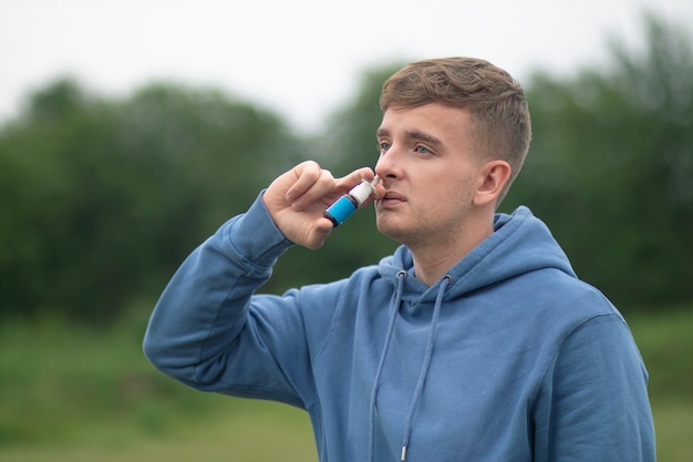 Junger kranker Mann benutzt Nasentropfen