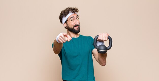 Junger kühler bärtiger Mann im Fitnessstudio mit einer Hantel. Sportkonzept