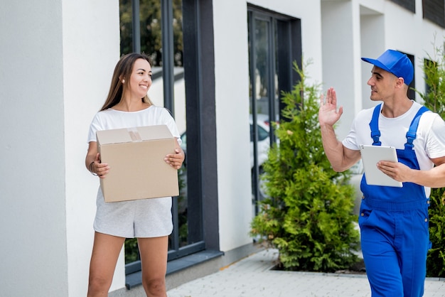 Junger Kurier liefert Waren an eine junge Frau zu Hause