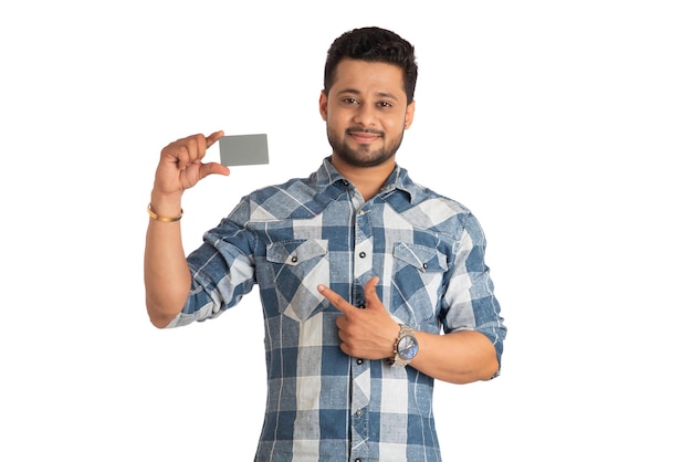 Junger lächelnder gutaussehender Mann, der mit einer Kredit- oder Debitkarte auf weißem Hintergrund aufwirft