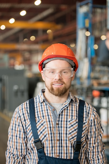 Junger lächelnder männlicher Ingenieur der Fabrik oder der Industrieanlage