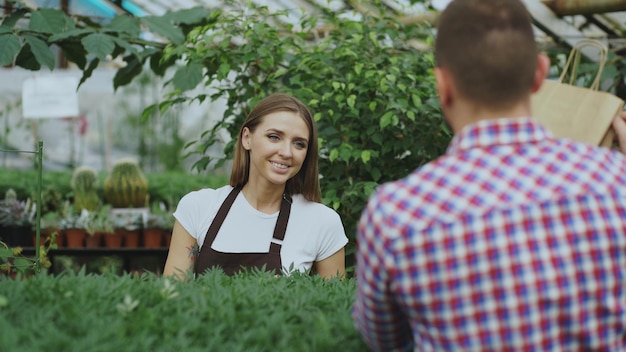 Junger lächelnder Verkäuferflorist, der im Gartencenter arbeitet