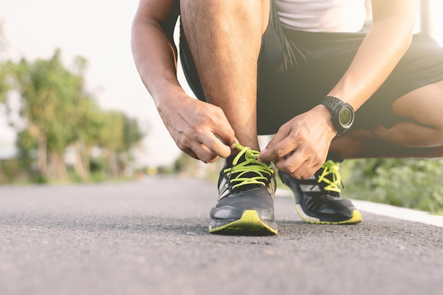 Junger Läufer Bindet die Schnürsenkel auf dem Laufsteg