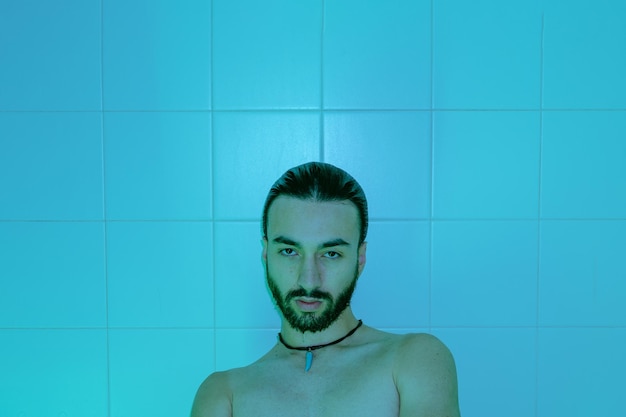Junger lateinamerikanischer Mann nass im Badezimmer nackt mit Blick auf ernsthafte Kamera künstlerischen Bildkopierraum