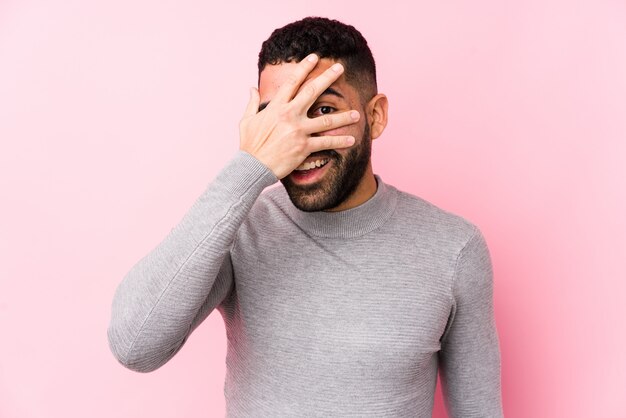 Junger lateinischer Mann gegen ein rosa Wand lokalisiertes Blinken