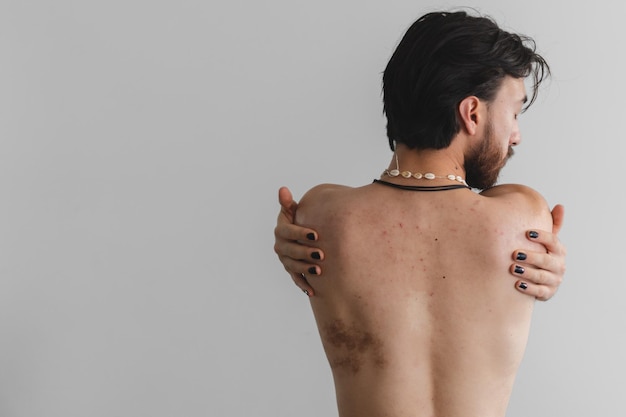 Junger lateinischer schwuler Queer-Mann auf dem Rücken nackt, der sich mit geschlossenen Augen umarmt Kopierbereich