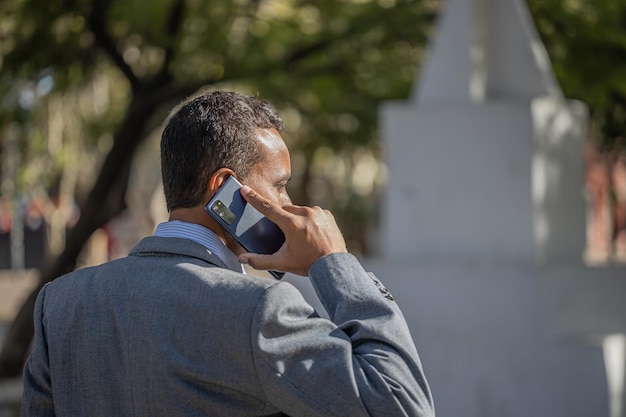 Junger Latino-Mann spricht auf dem Mobiltelefon mit Kopierplatz