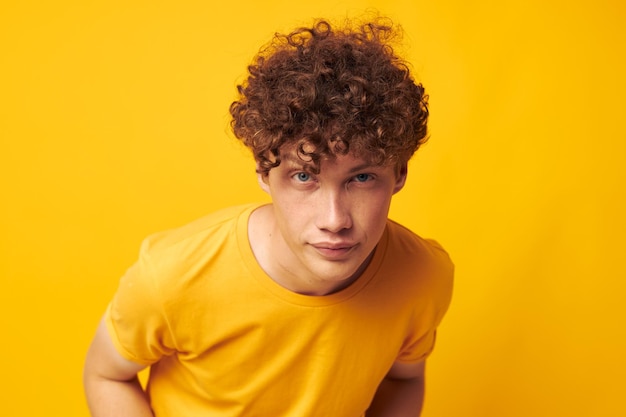 Junger lockiger Mann, gelbes T-Shirt, Brille, Mode, Handgesten, gelber Hintergrund, unverändert