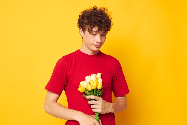 Junger lockiger mann in einem roten t-shirt ein blumenstrauß urlaubsgeschenk lebensstil unverändert