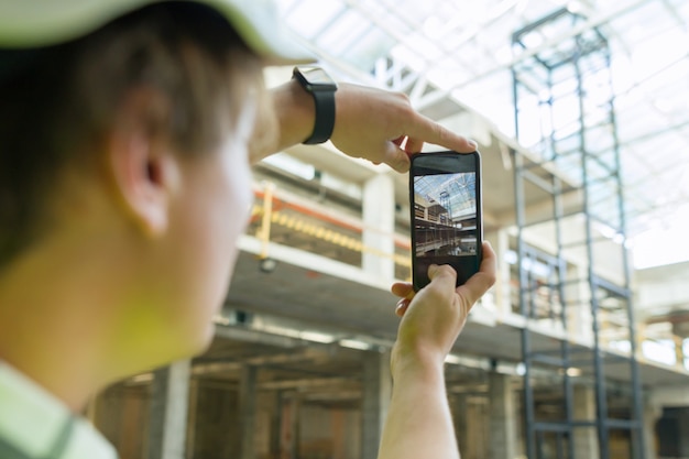 Junger männlicher Architekt fotografiert Baustelle