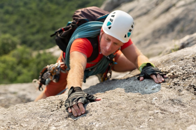 Junger männlicher Bergsteiger klettert auf einer schwierigen Route auf einen Berg