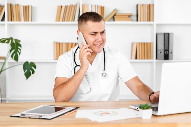 Junger männlicher Doktor, der am Telefon spricht