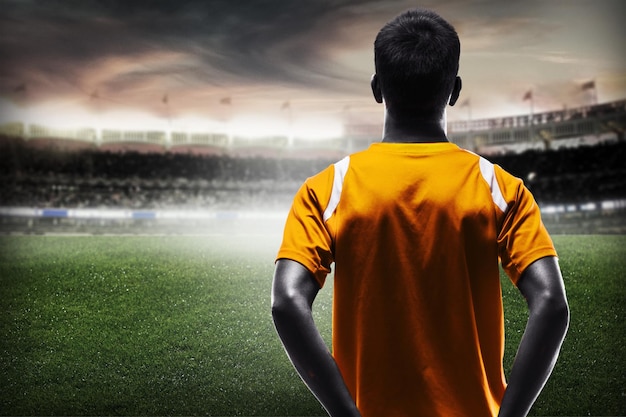 Junger männlicher Fußballspieler auf unscharfem Sportstadionhintergrund