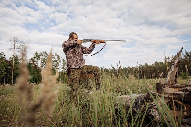 Junger männlicher Jäger in Tarnkleidung bereit, mit Jagdgewehr zu jagen