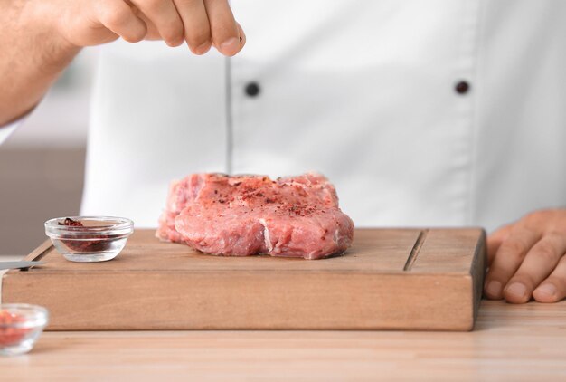 Junger männlicher Koch, der Fleisch in der Küche kocht