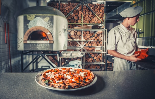 Foto junger männlicher koch gekochte pizza im restaurant?