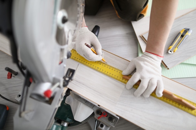 Junger männlicher Mechaniker ist Markup-Holzplatte mit Bleistift und Lineal vor dem Schneiden