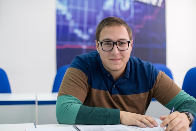 junger männlicher student, der notizen im klassenzimmer schreibt