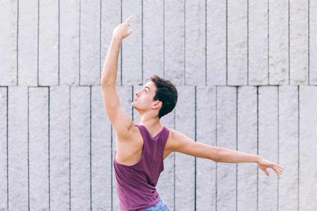 Junger männlicher Tänzer, der eine Eleganzballetthaltung schlägt