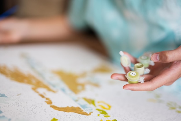 Junger männlicher Teenager malt Bild nach Zahlen auf Leinwand im heimischen Wohnzimmer Hobby und Freizeit ca