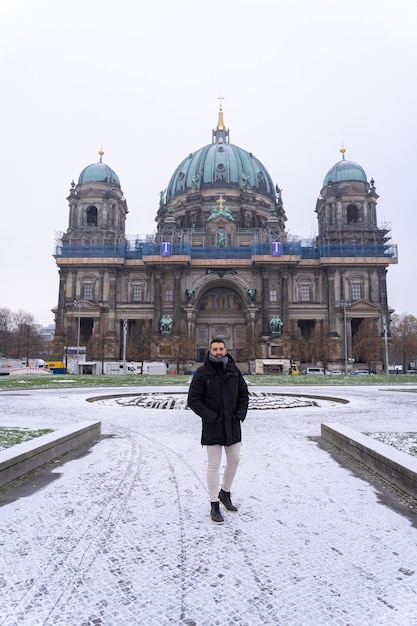 Junger männlicher Tourist, der im Park vor dem Berliner Dom mit Schnee auf dem ganzen Boden spaziert