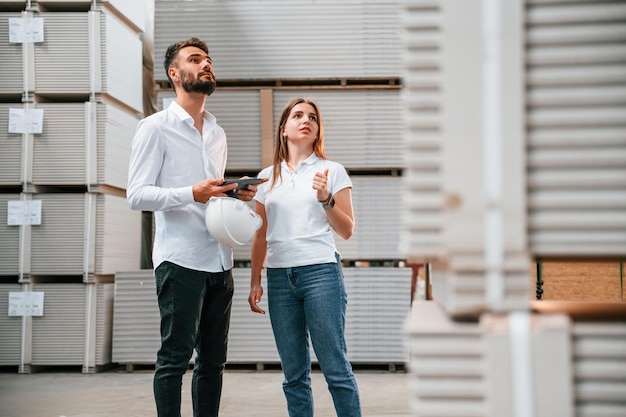 Junger Manager in formeller Kleidung arbeitet mit Frau im Lager