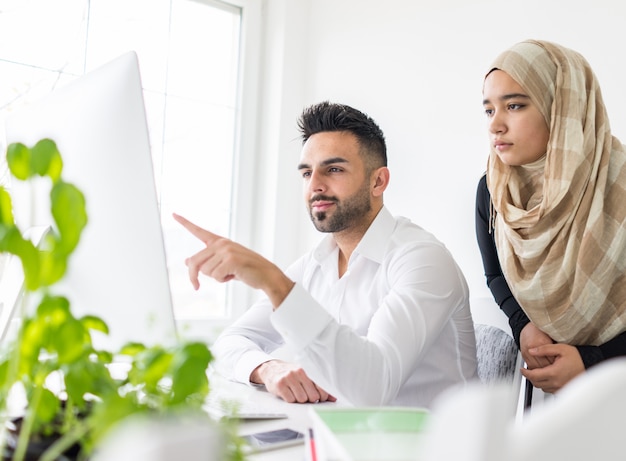 Junger mand und Frau, die im Büro auf Computer arbeitet